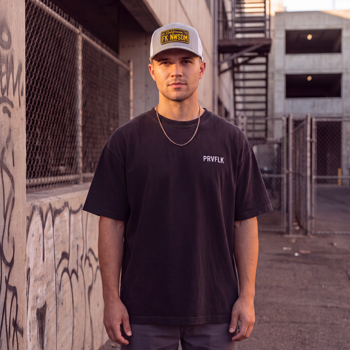 Man wearing FK NWSOM California hat and PRVFLK tee in an urban alley